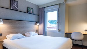 A hotel room with a large bed, a desk, and a chair. - ibis Agen Centre (Agen)