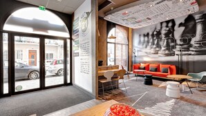 A modern interior with a reception desk, seating area, and a chess-themed wall mural. - ibis Agen Centre (Agen)