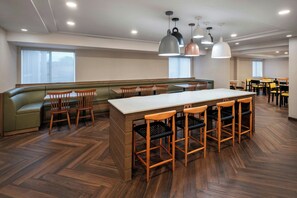 Un comedor amplio con una barra larga, múltiples sillas de madera y un banco acolchado verde.