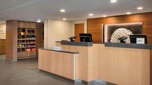 A hotel reception desk with a wooden finish, a digital screen, and a nameplate. - Fairfield Inn By Marriott Amesbury (Amesbury)
