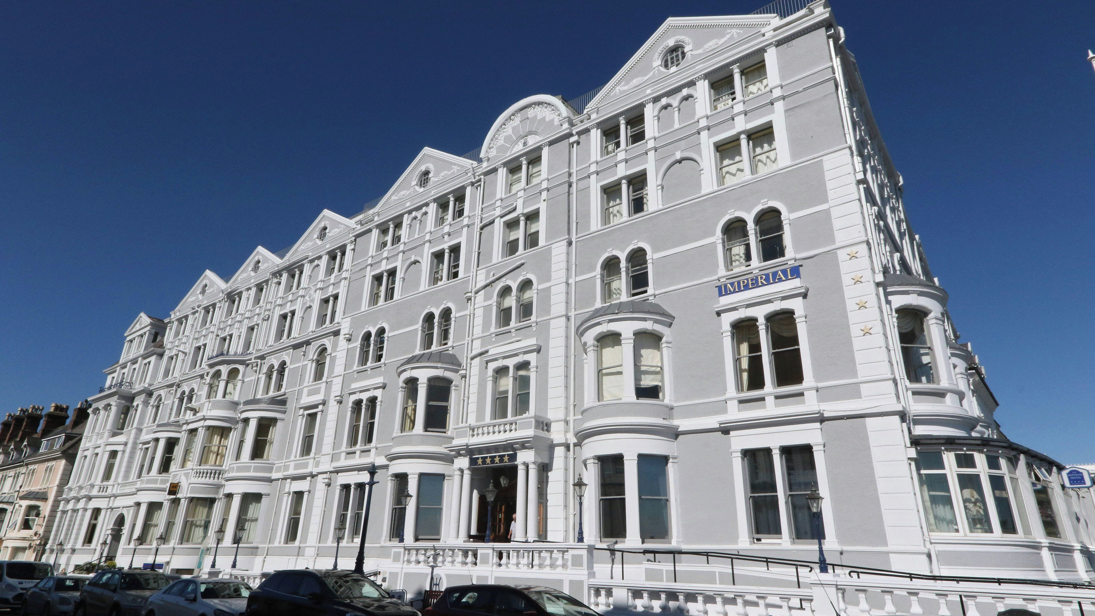 Un immeuble à plusieurs étages de style architectural classique, dont la façade est ornée d’une grande enseigne portant l’inscription « IMPERIAL ».