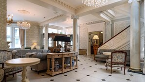 A spacious living room with a grand staircase, elegant furniture, and a chandelier. - Imperial Hotel (Llandudno)
