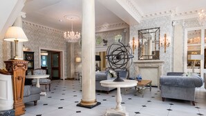 A spacious lobby with a high ceiling, ornate columns, a grand chandelier, and a fireplace. - Imperial Hotel (Llandudno)
