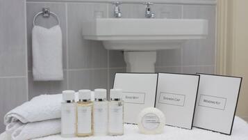 A bathroom with a white sink, a towel, and various toiletries including bottles and a soap bar.