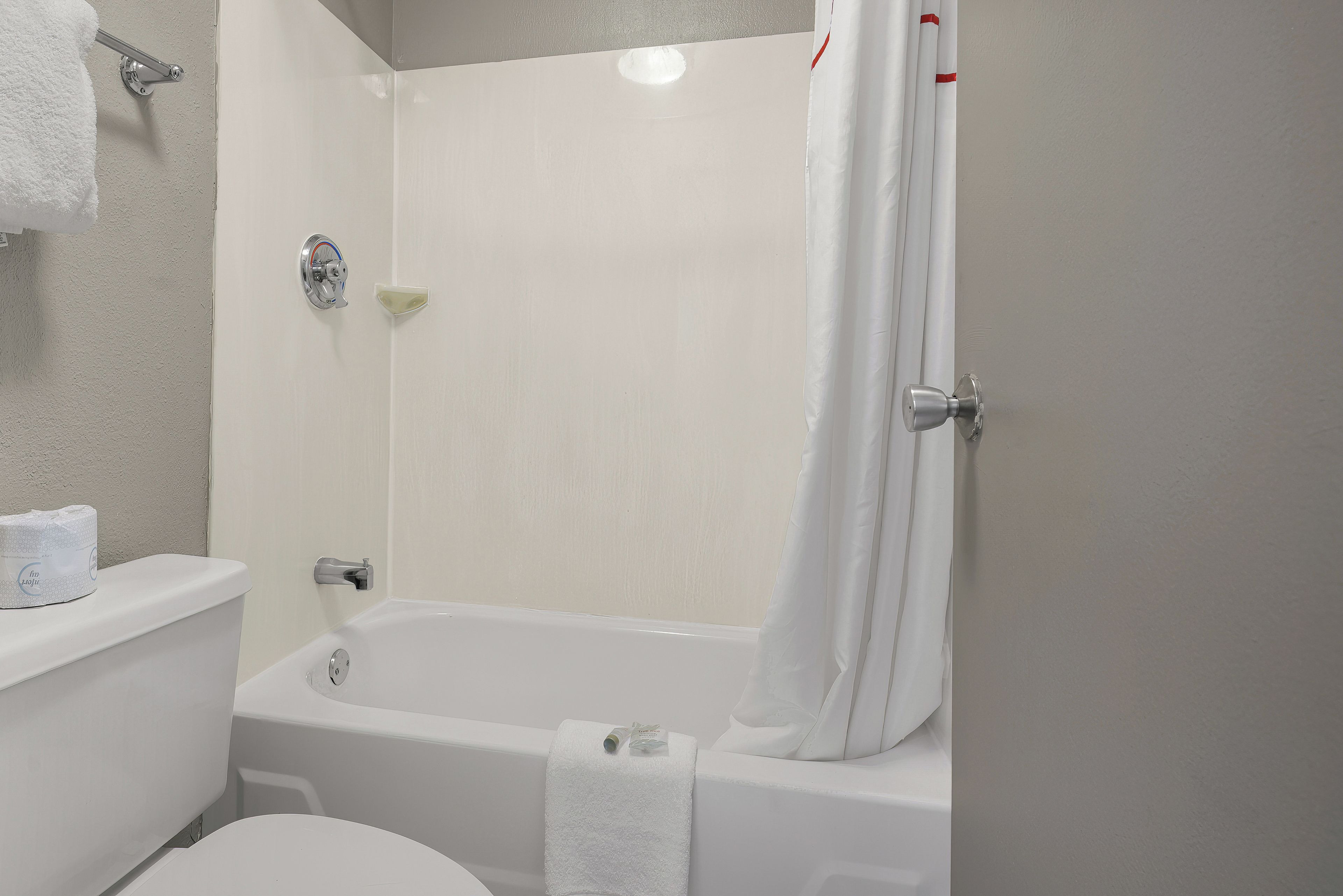 A bathroom with a bathtub, toilet, and a towel rack.