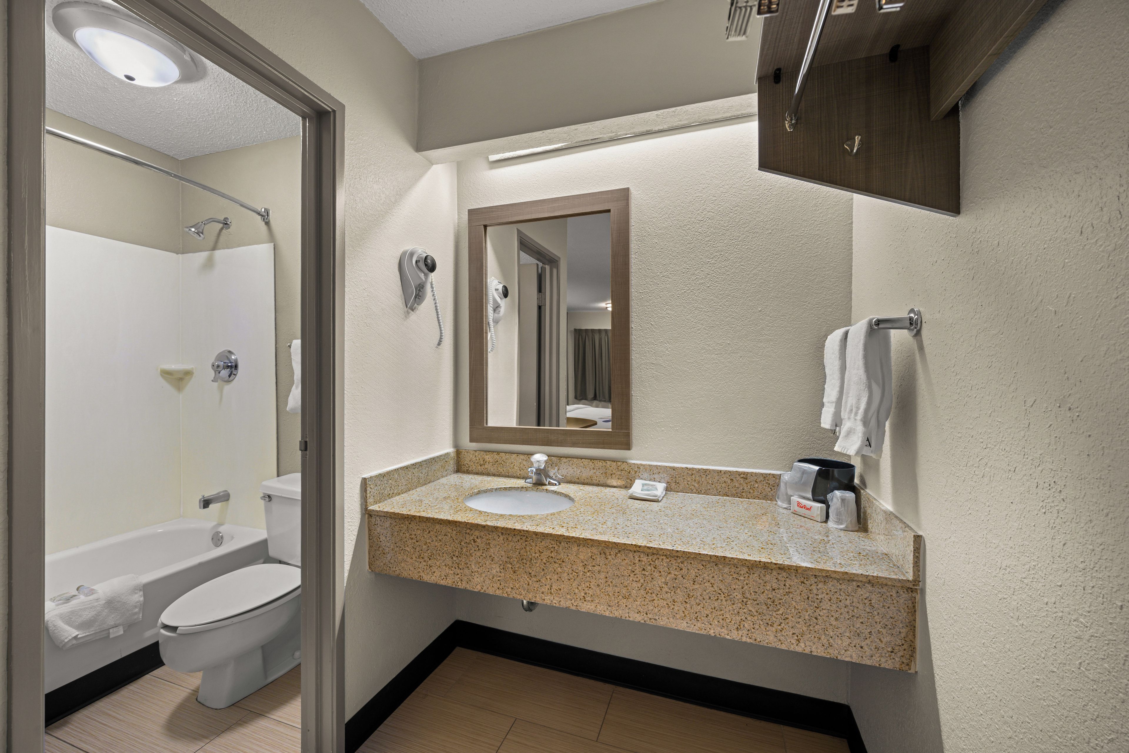 A bathroom with a toilet, sink, mirror, and towel rack.