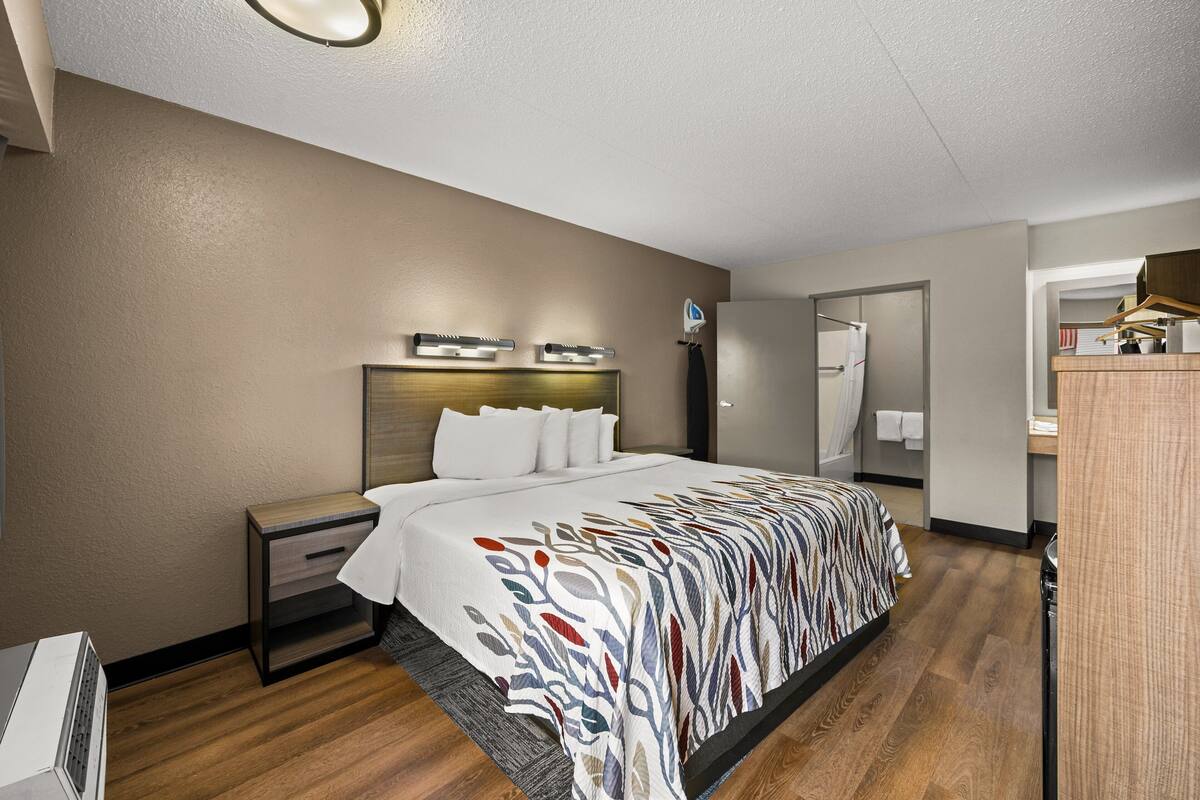 A hotel room with a large bed, bedside tables, a mirror, and a wardrobe.