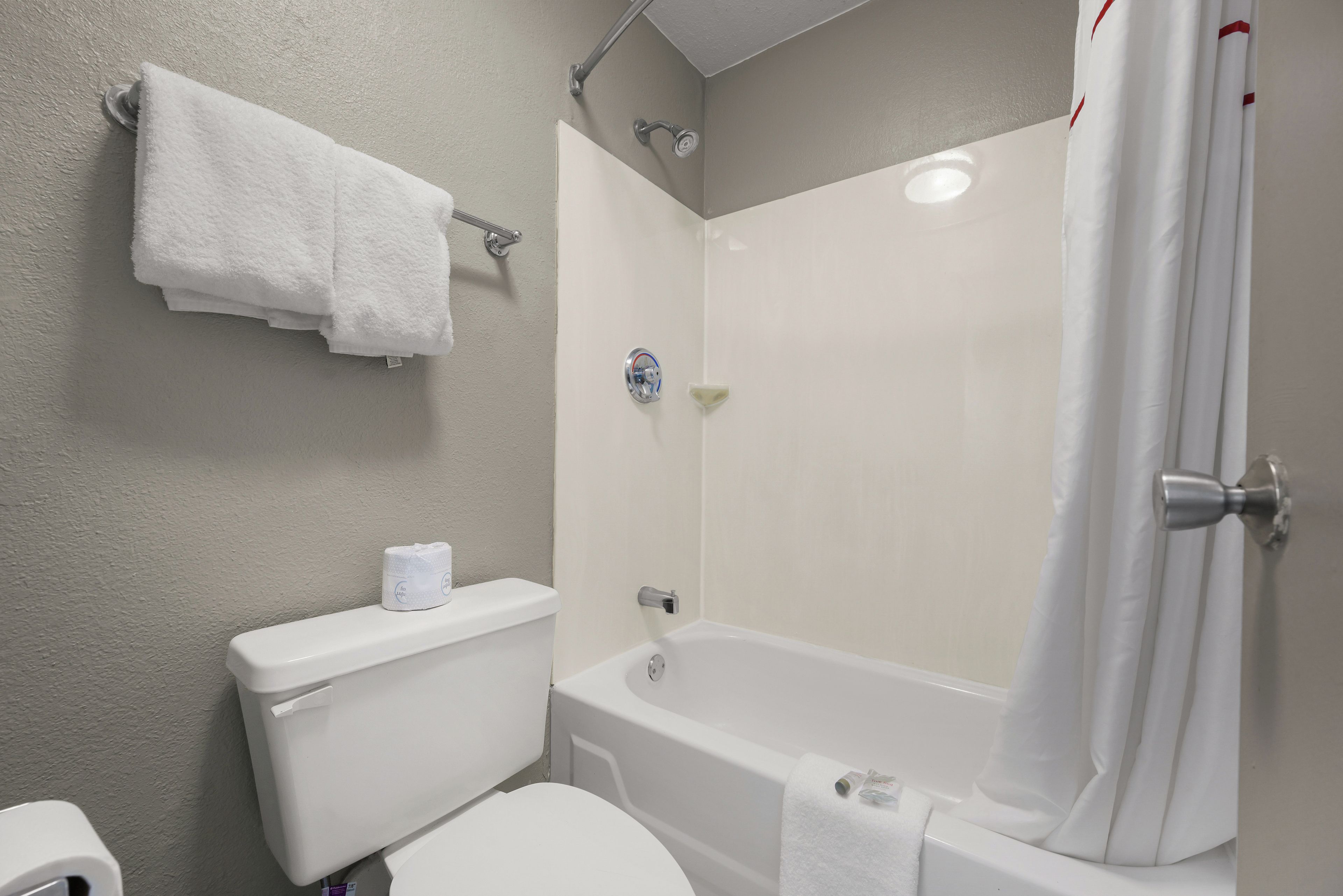 A bathroom with a toilet, a bathtub, and a shower curtain.