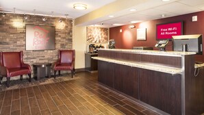 A reception area with a counter, two leather chairs, a coffee machine, and a sign indicating free Wi-Fi in all rooms. - Red Roof Inn Detroit - Royal Oak/ Madison Heights (Madison Heights)