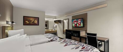 A hotel room with two beds, a desk, a television, and a mirror.