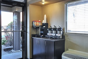 A kitchenette with a coffee machine, hot water dispenser, and condiment dispensers. - Red Roof Inn Detroit - Royal Oak/ Madison Heights (Madison Heights)