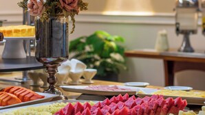 A buffet table with various fruits and a floral centerpiece. - Braston Augusta by Castelo Itaipava (São Paulo)