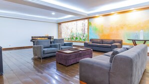 A spacious living room with a piano, sofas, and a large window with a view of greenery. - Braston Augusta by Castelo Itaipava (São Paulo)