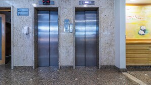 Two elevators in a lobby with a marble floor, a sign for 'Masp Metropolitan', and a digital clock above the left elevator. - Braston Augusta by Castelo Itaipava (São Paulo)