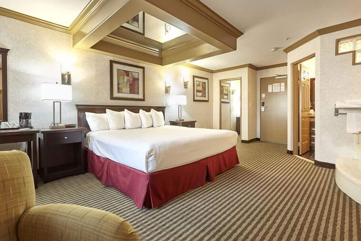 A hotel room with a large bed, a desk with a lamp, a chair, and a bathroom with a bathtub.