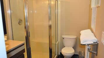 A bathroom with a glass-enclosed shower, a toilet, and a sink with a towel rack.
