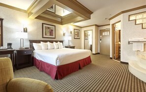 A hotel room with a large bed, a desk with a lamp, a chair, and a bathroom with a bathtub.