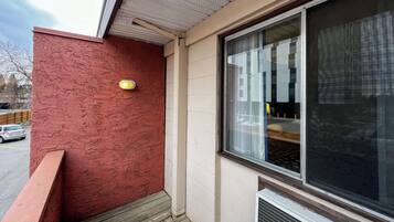 A building exterior with a red textured wall, a large window with a view of the interior, and a small yellow sign on the wall.