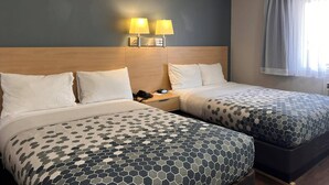 A hotel room with two beds, a nightstand, a lamp, and a window with curtains. - Econo Lodge Motel Village (Calgary)