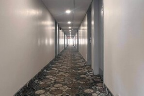 A long, narrow hallway with patterned carpet, white walls, and doors on both sides.