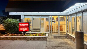 A hotel entrance with a 'Welcome' sign, a 'No parking' sign, and a guest registration area. - Econo Lodge Motel Village (Calgary)