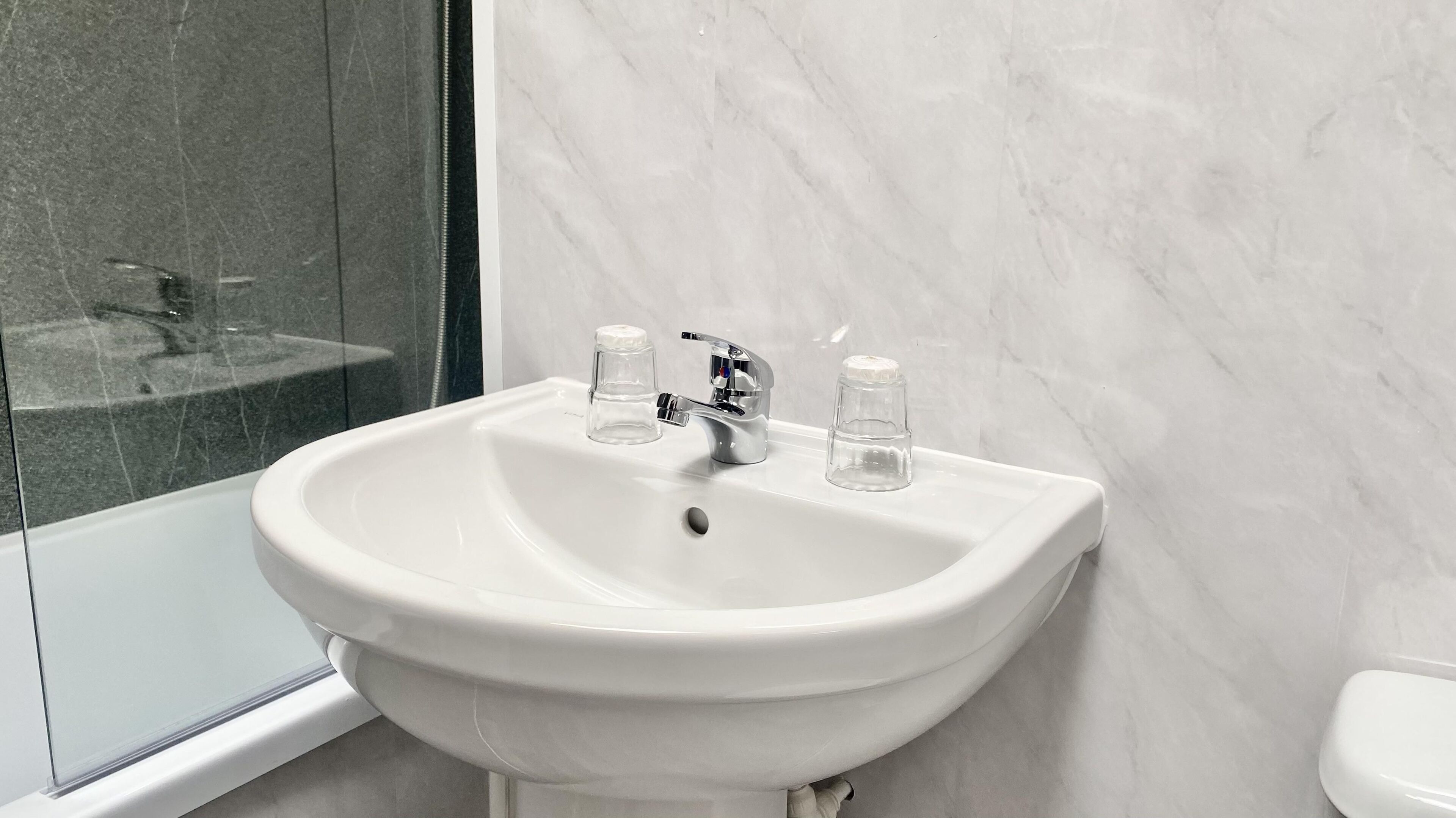 Une salle de bain avec un lavabo blanc, un miroir et des toilettes.
