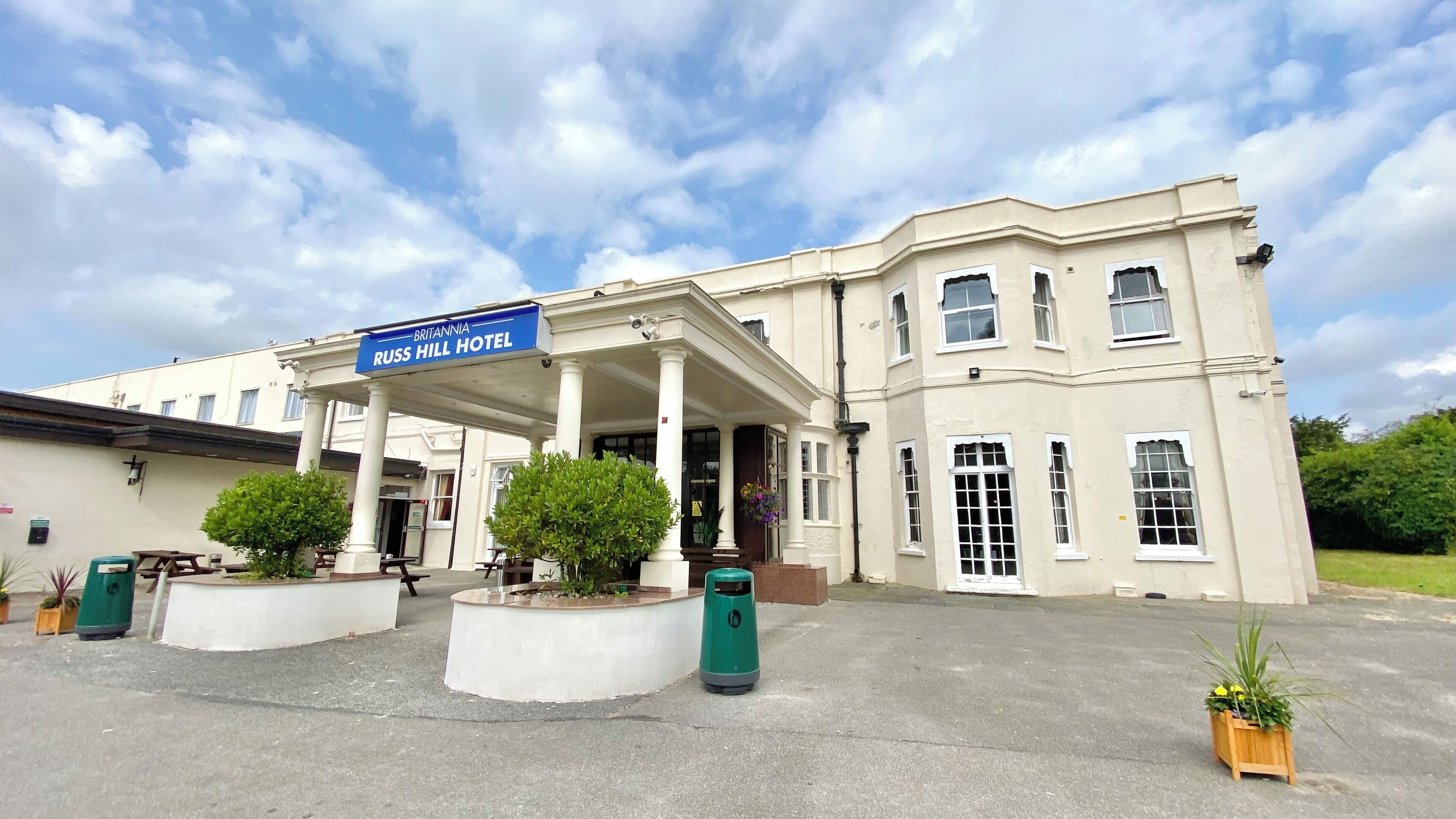 Das Russ Hill Hotel mit einer überdachten Einfahrt, Säulen und Kübelpflanzen.