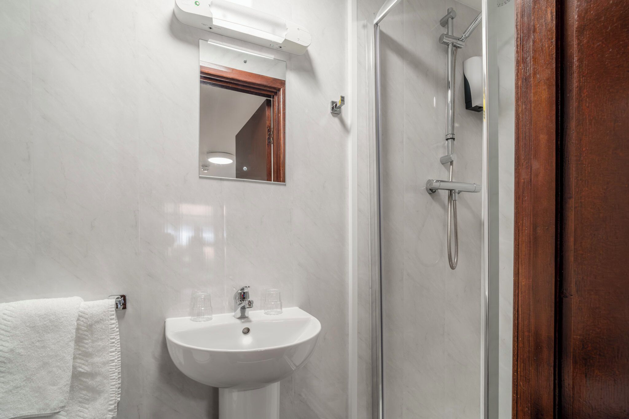 A bathroom with a white sink, a mirror, and a shower.