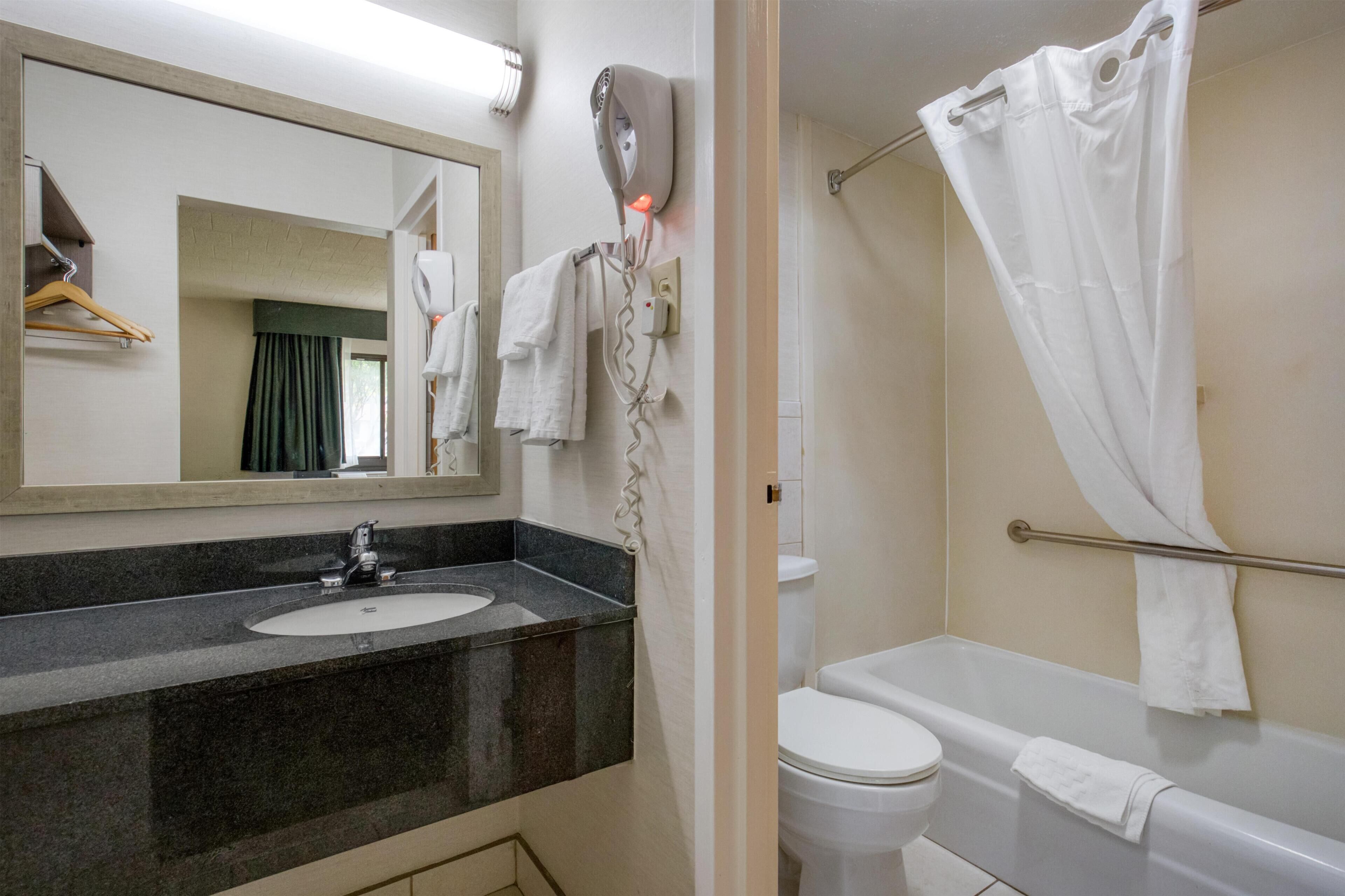 A bathroom with a sink, mirror, towel rack, and a shower curtain.