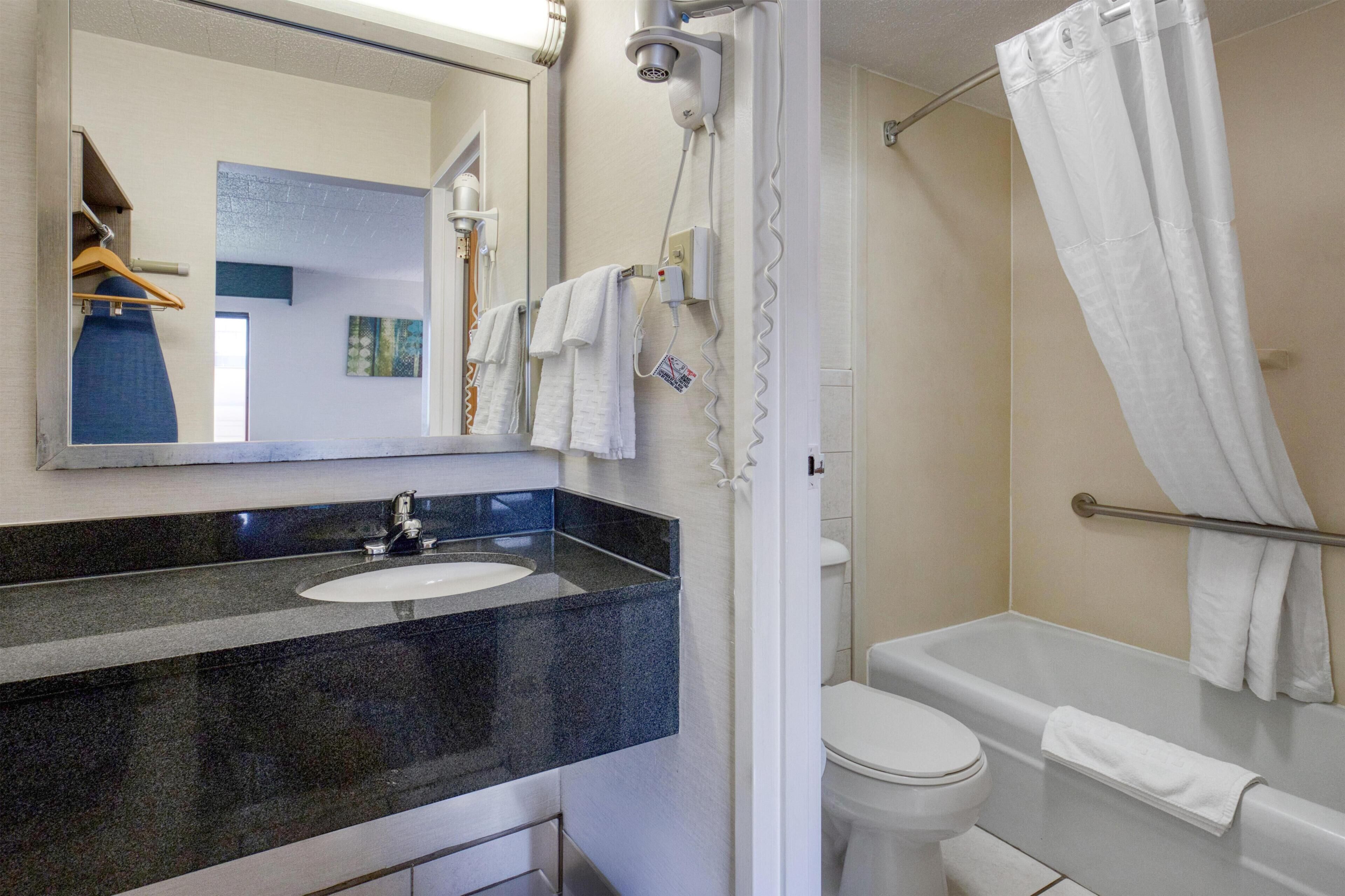 A bathroom with a sink, mirror, shower, and toilet.