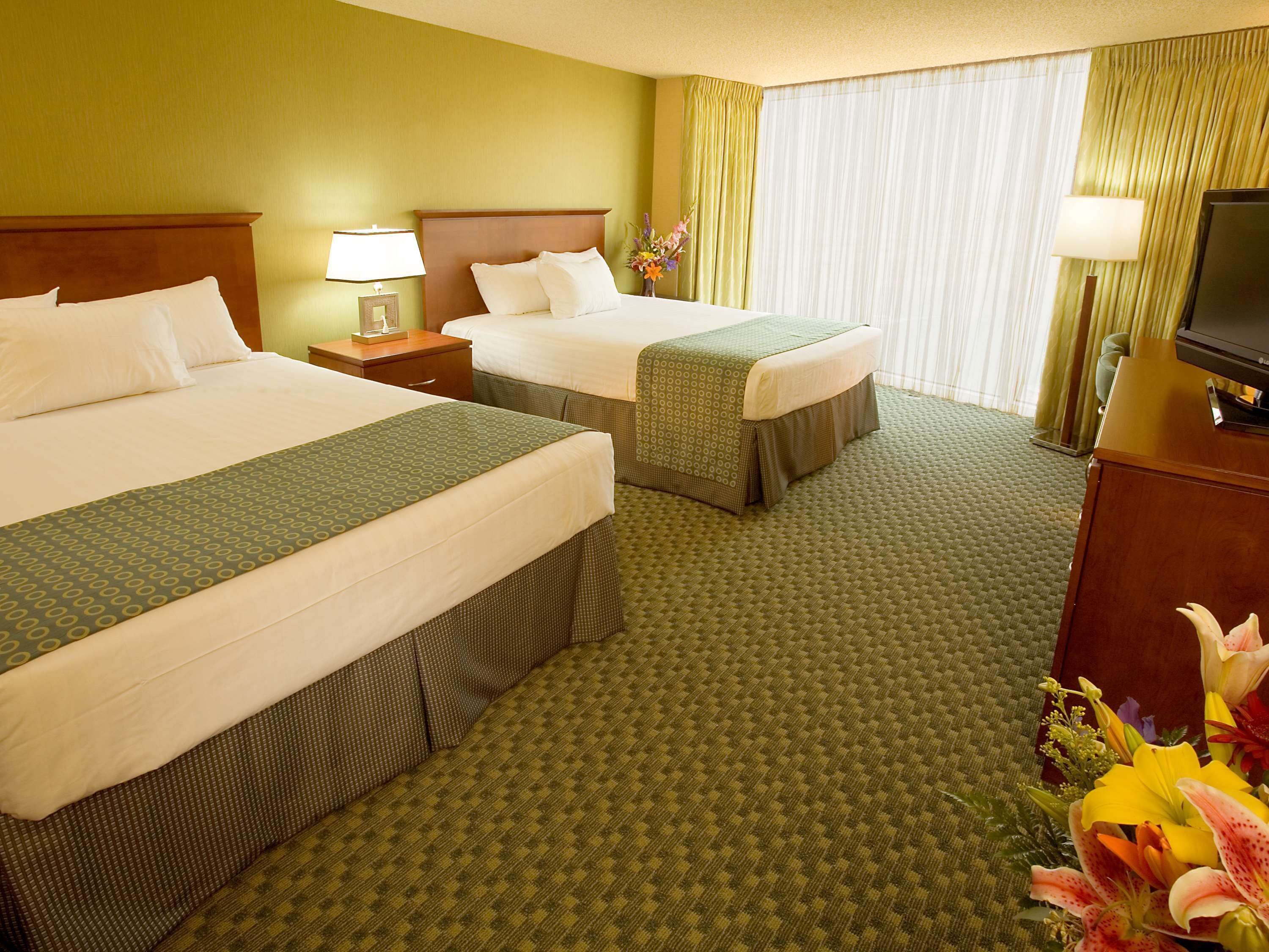 Habitación de hotel con dos camas, televisión y un arreglo floral.