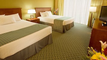 A hotel room with two beds, a television, and a floral arrangement.