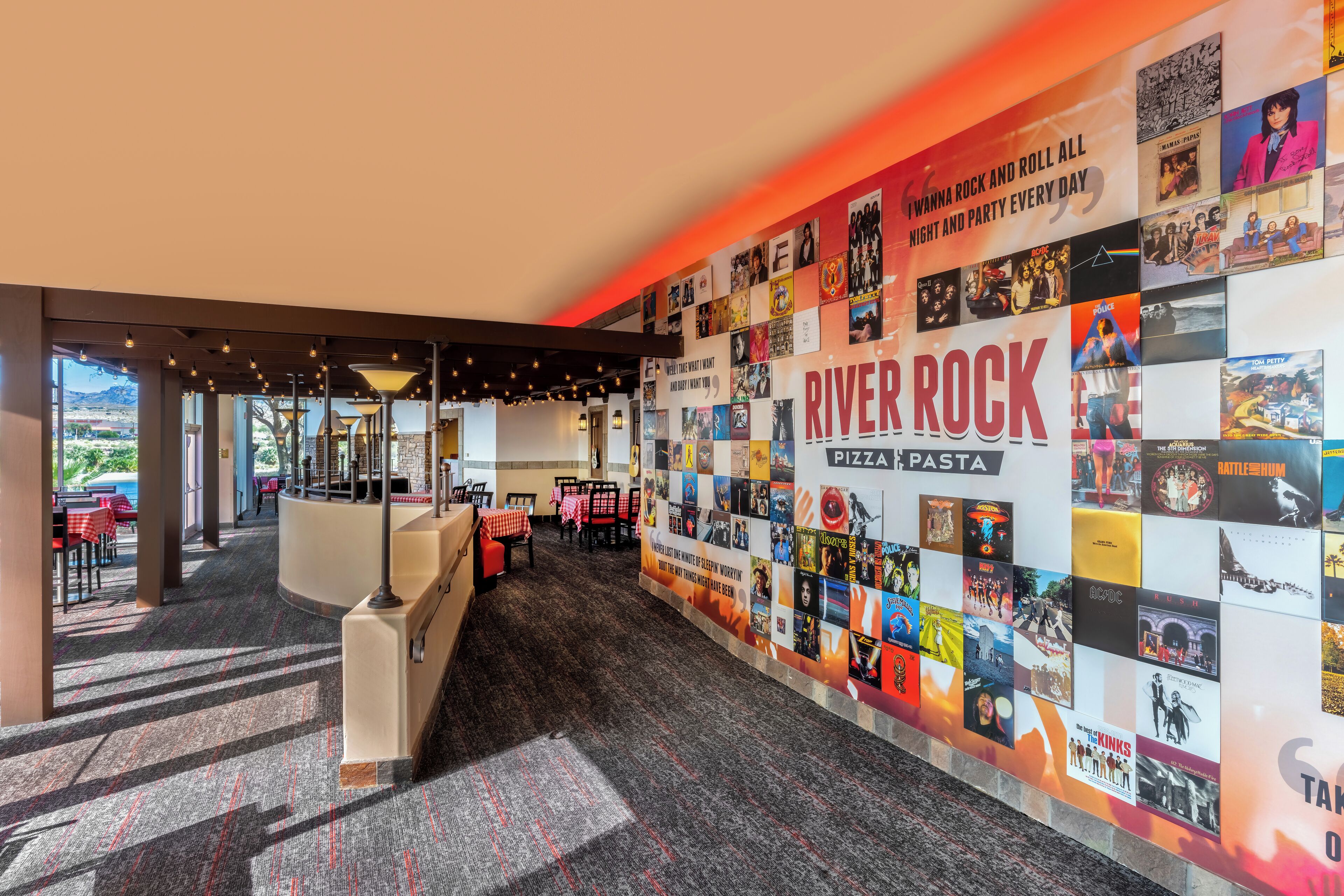Un restaurant dont un mur est décoré de divers affiches et sur lequel on peut lire l’inscription « River Rock Pizza Pasta ».