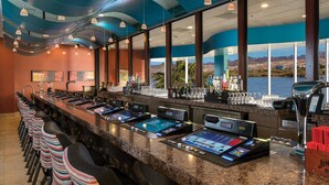 A bar area with a long counter, multiple bar stools, and a view of the outdoors. - The Aquarius Casino Resort, BW Premier Collection (Laughlin)
