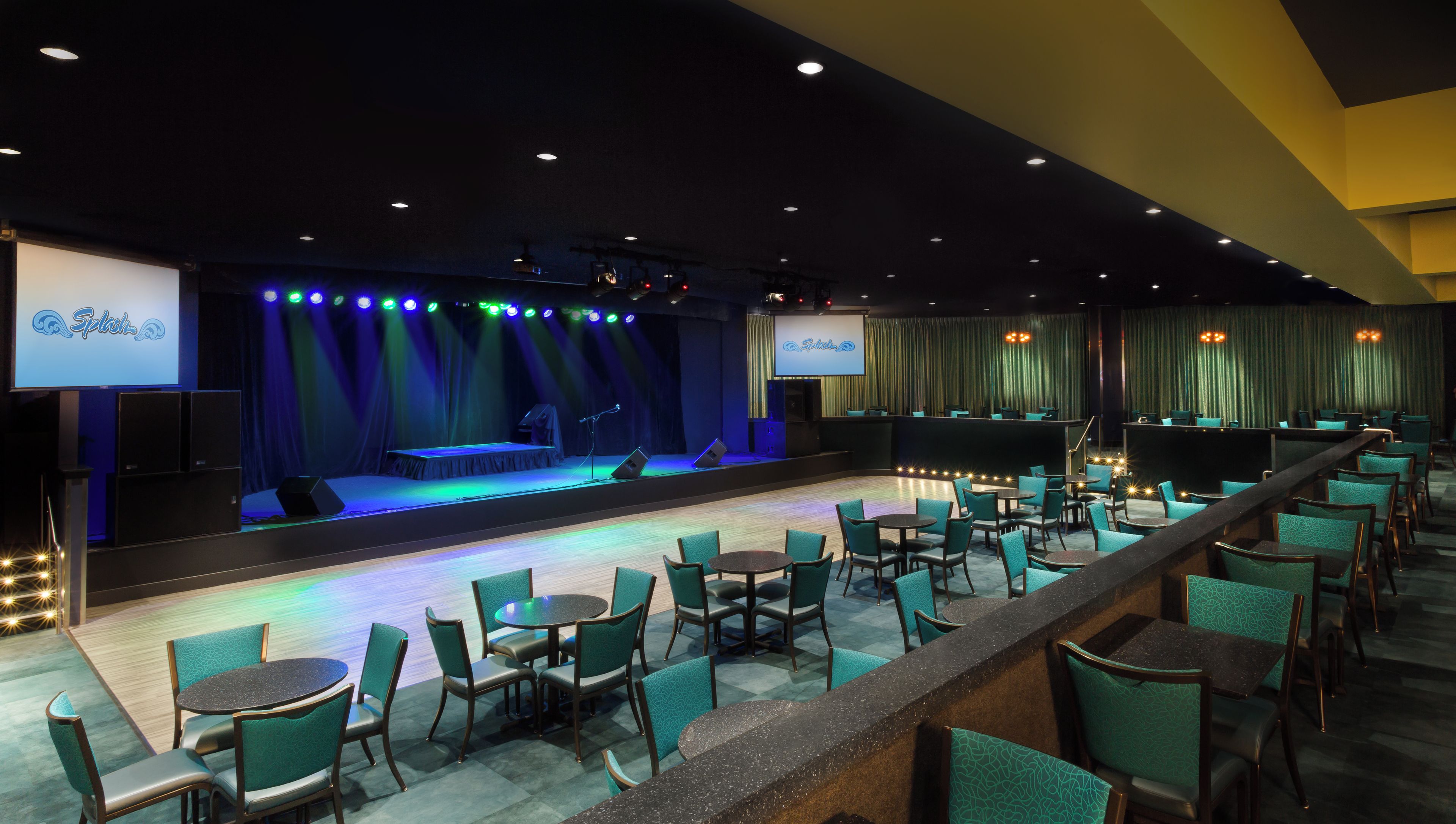 A conference room with a stage, a large screen, and rows of chairs.