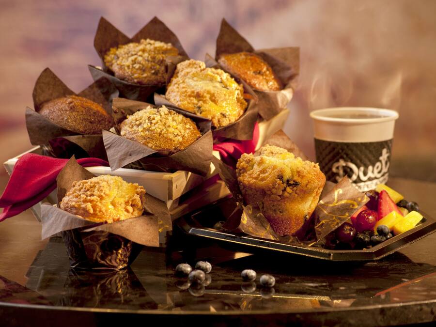 Un plateau avec des muffins et une tasse de café, sur un fond flou.