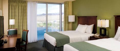 A hotel room with two beds, a desk, and a chair. There is a large window with curtains, a lamp, and a view of a landscape.
