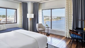A hotel room with a large bed, a chair, a small table, and a view of a body of water. - Annapolis Waterfront Hotel, Autograph Collection (Annapolis)