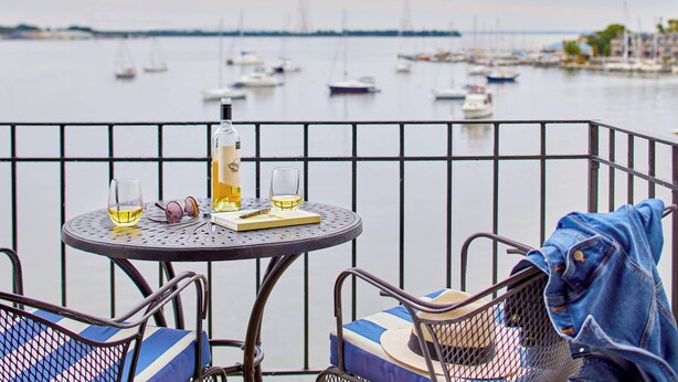 A balcony with a table set for two, overlooking a marina with boats. - Annapolis Waterfront Hotel, Autograph Collection (Annapolis)