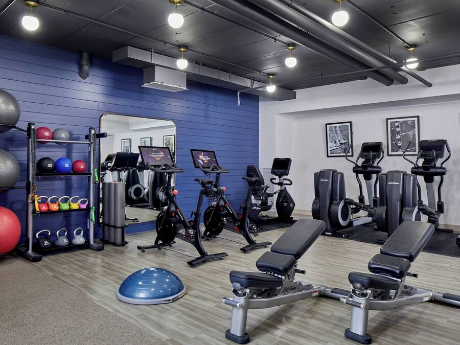 A gym with exercise equipment, a mirror, and a blue wall.