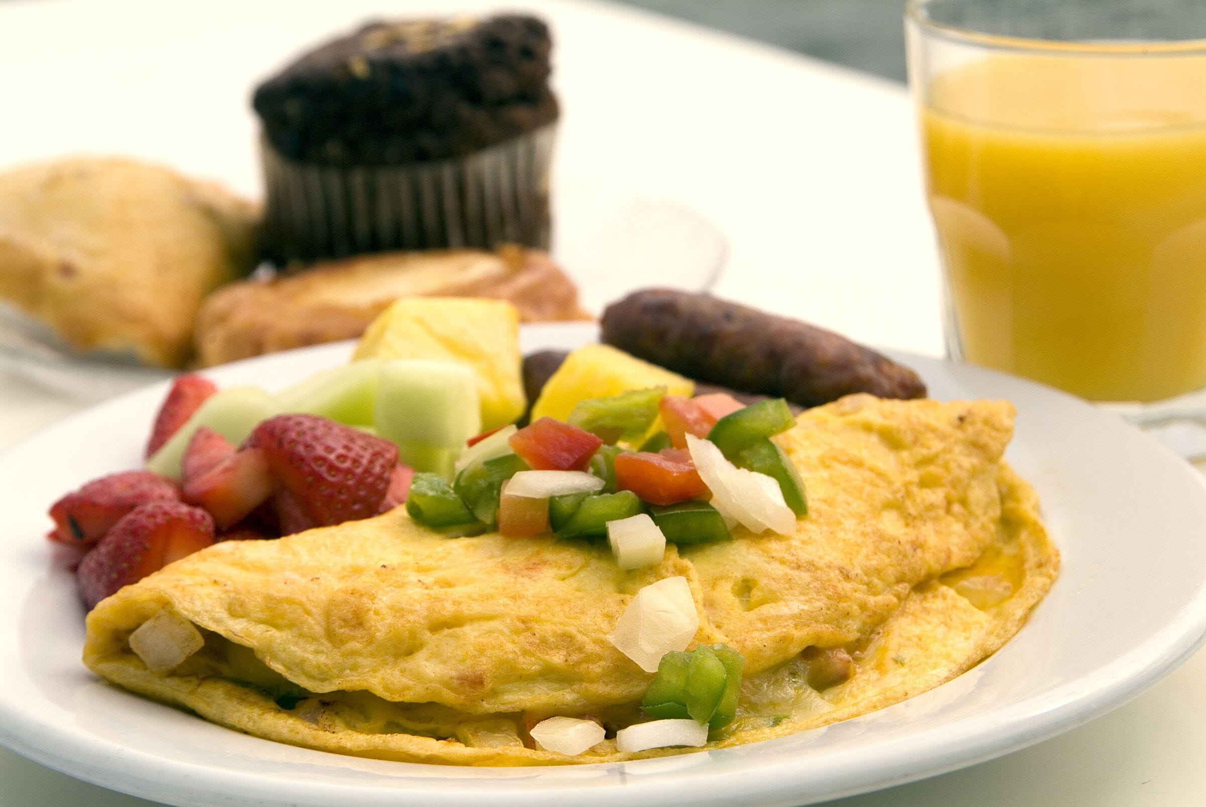 A plate with an omelette, strawberries, and a glass of orange juice.