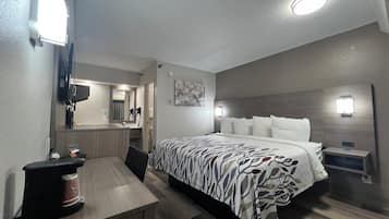 Hotellihuone, jossa on sänky, yöpöytä ja työpöytä sekä kahvinkeitin.