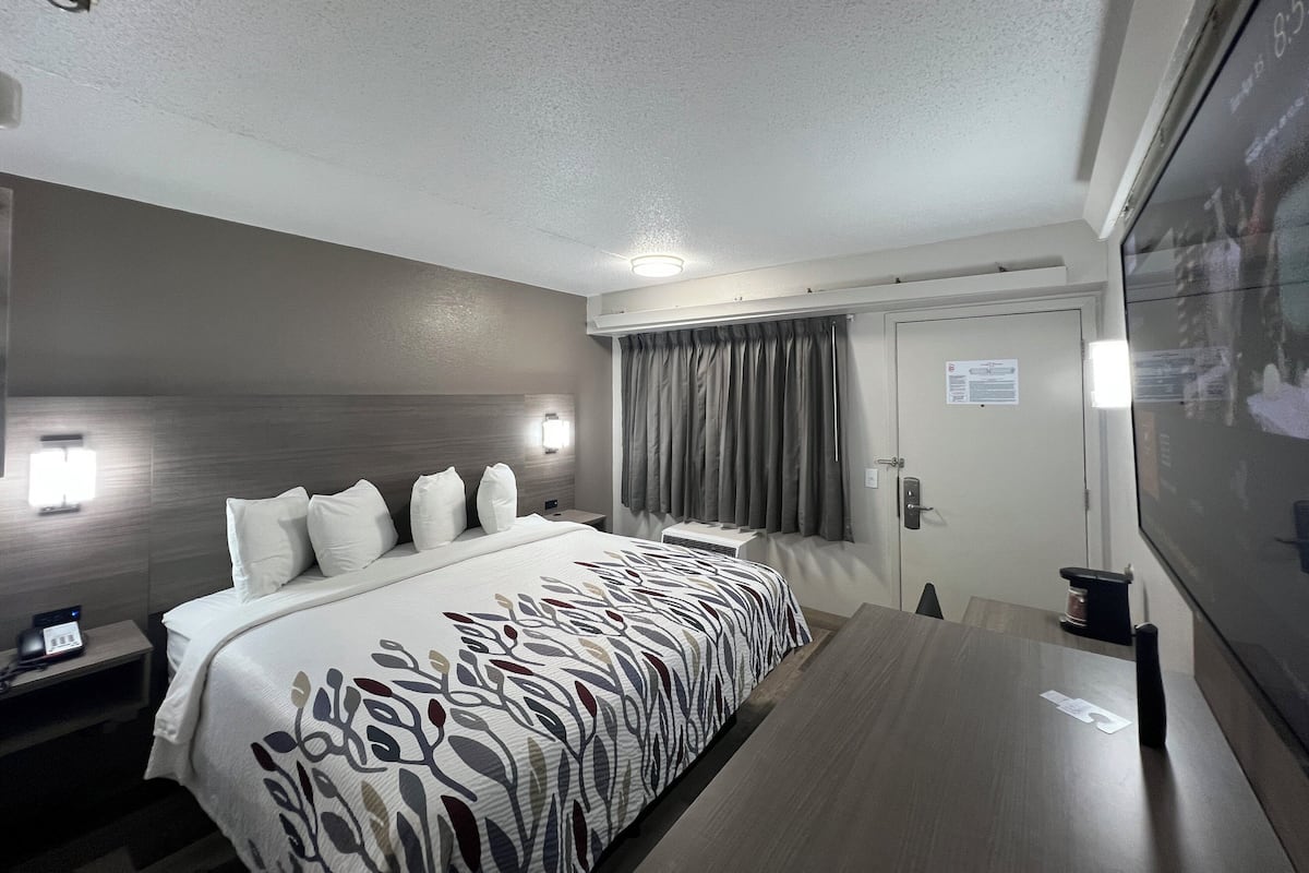 Moderni hotellihuone, jossa on suuri sänky, yöpöydät, työpöytä ja näkymä ulos.