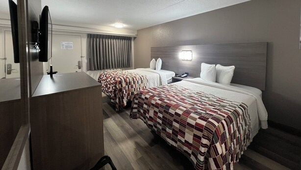 A hotel room with two beds, a desk, and a television. - Red Roof Inn Lexington South (Lexington)