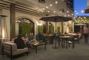 An outdoor dining area with tables and chairs, string lights, and a green wall. - Doubletree by Hilton Campbell - Pruneyard Plaza (Campbell)
