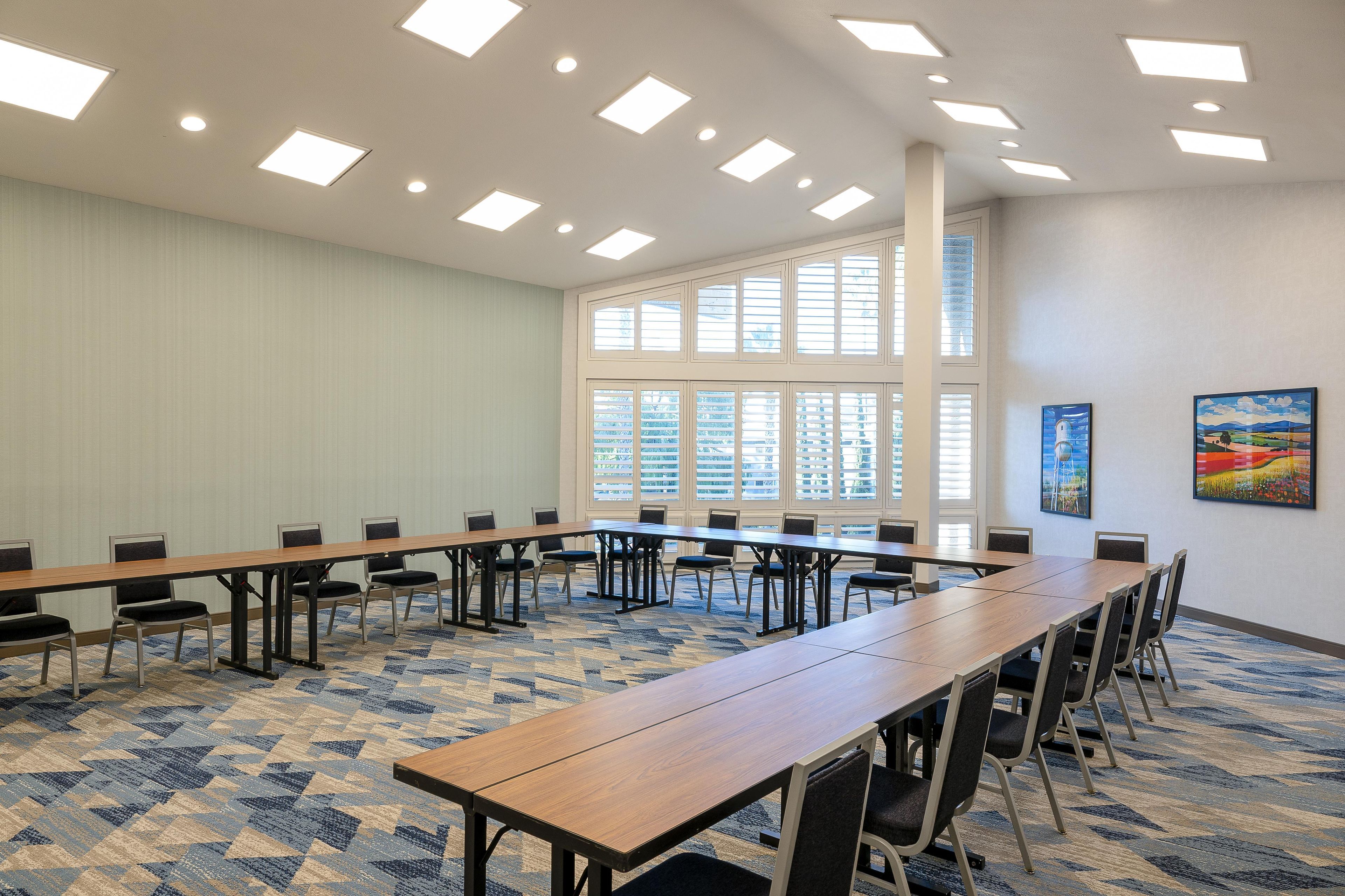 A conference room with a long table, chairs, and a carpeted floor.