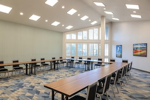 Una sala de conferencias con una mesa larga, sillas y suelo alfombrado.