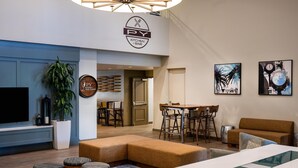 Un moderno vestíbulo de hotel con una zona de estar, un bar y un televisor.