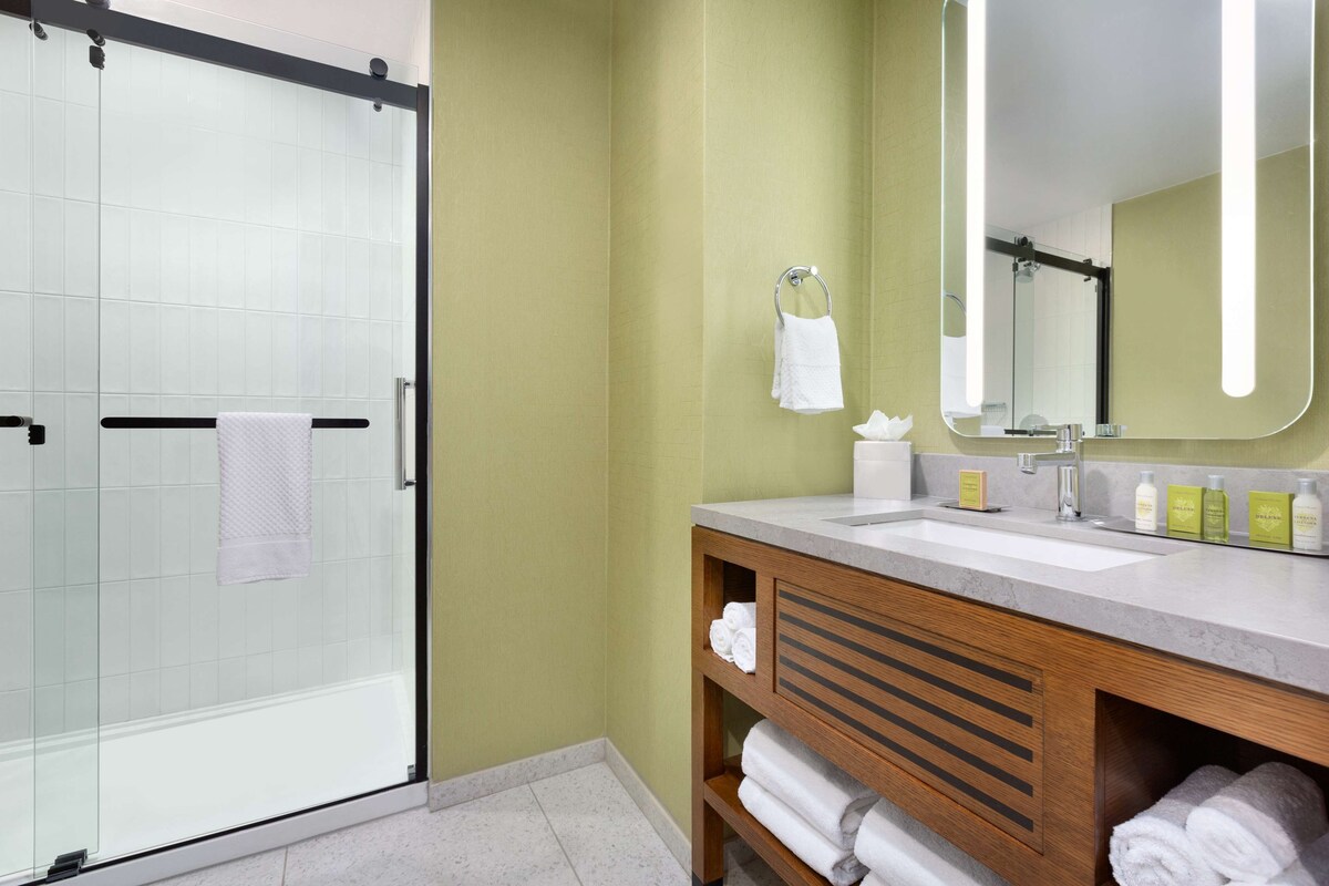 Une salle de bain moderne avec une douche à parois de verre, un meuble-lavabo en bois et un miroir.