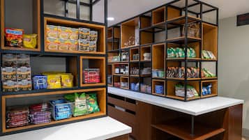 Una despensa bien organizada con estantes llenos de aperitivos, bebidas y salsas.